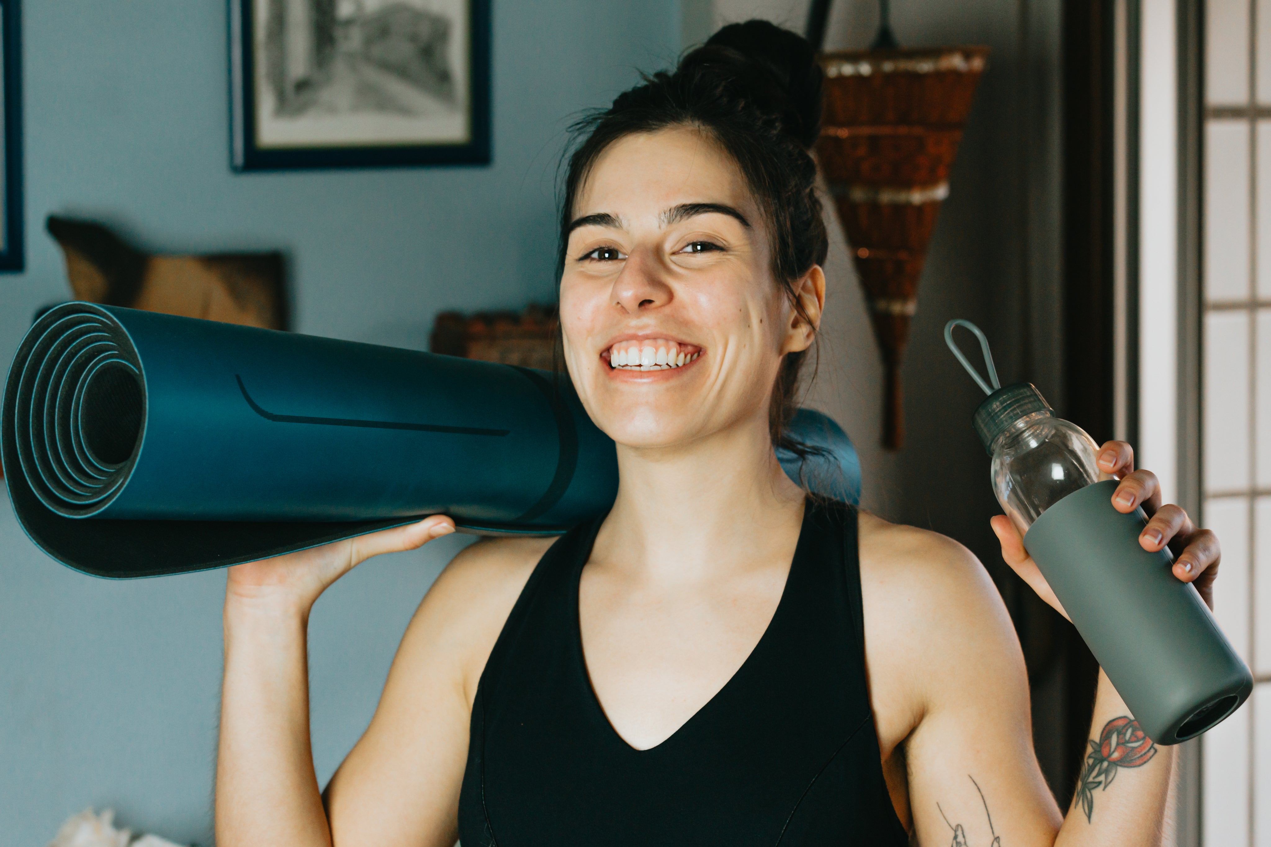 files/a-person-smiles-holding-a-water-bottle-and-a-yoga-mat.jpg